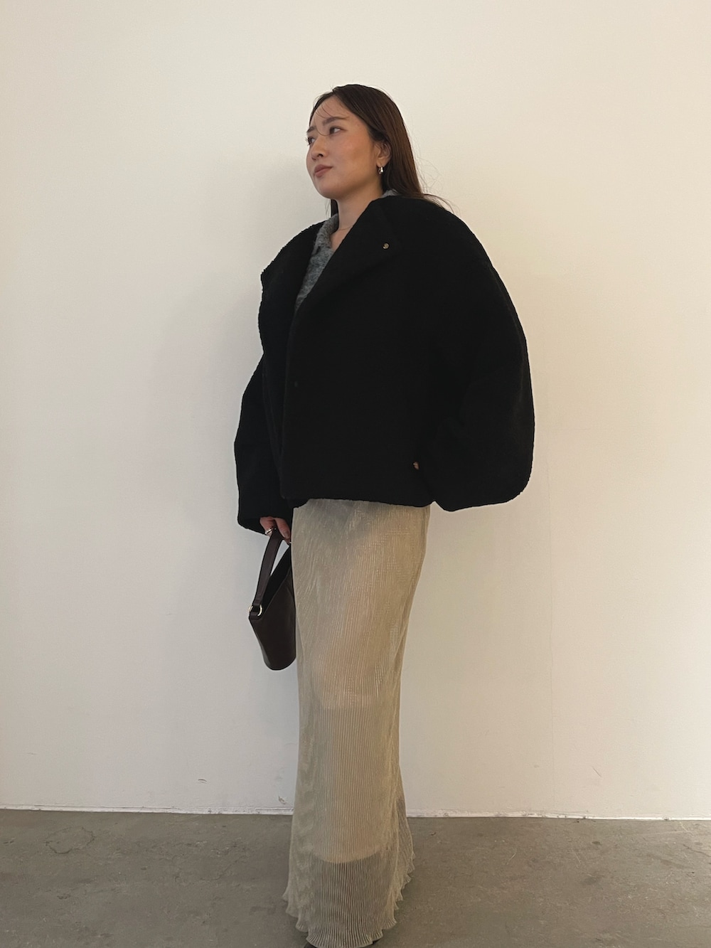 ブラック系のブルゾン、ブラウン系のハンドバッグ、ブラウン系のブーツを着用したレディースの秋コーディネートの6枚目の写真