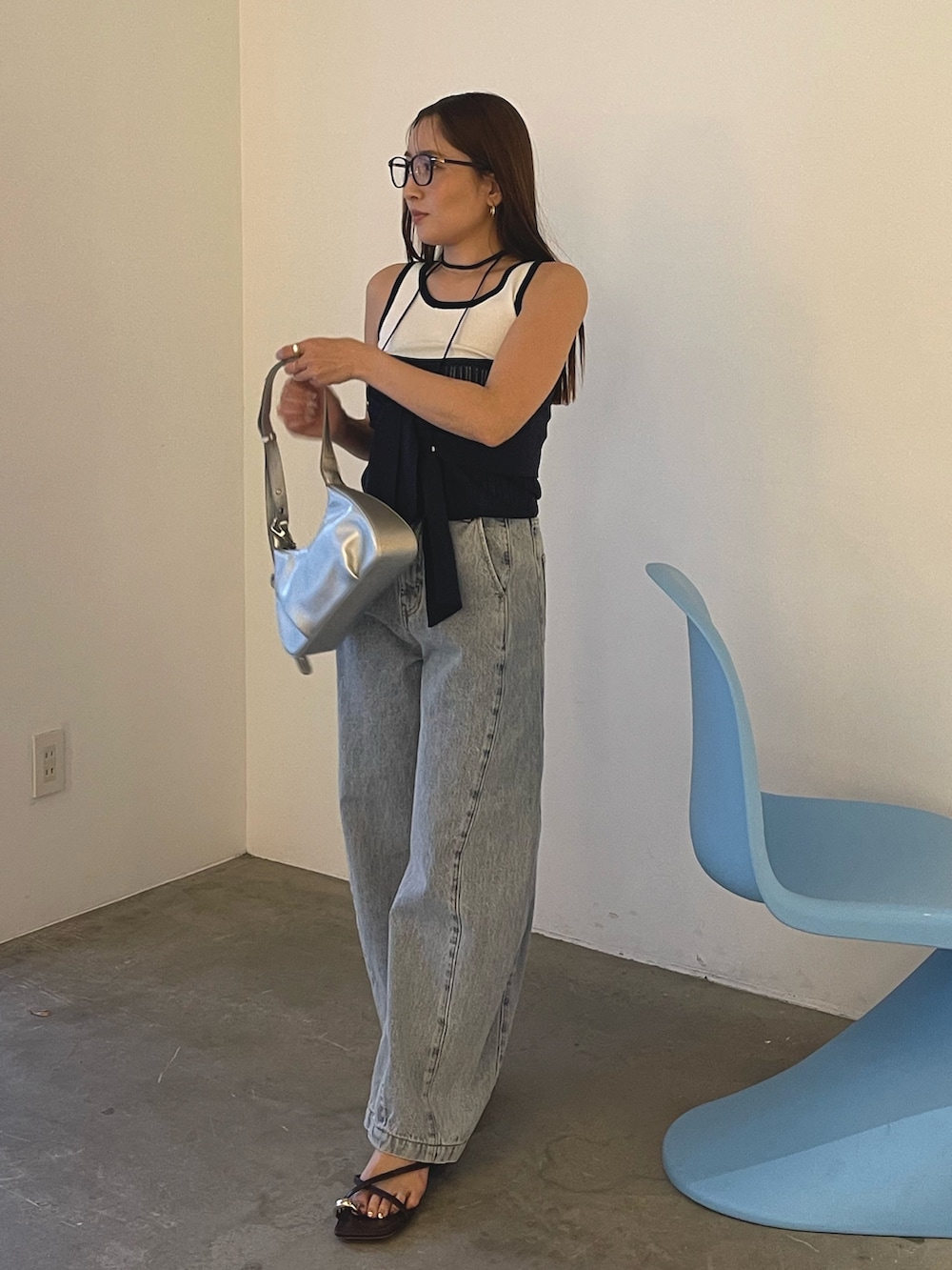 ブルー系のデニムパンツ、シルバー系のハンドバッグ、ブラウン系のサンダルを着用したレディースの春コーディネートの3枚目の写真