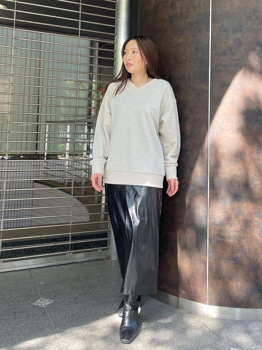 ブラック系のブーツ、ブラック系のスカート、ベージュ系のスウェットを着用したレディースの夏コーディネートの2枚目の写真