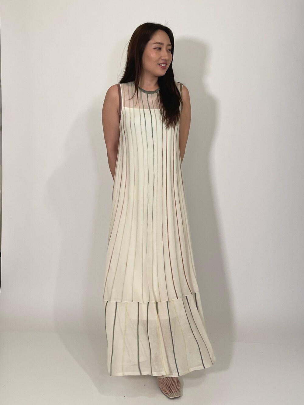 ホワイト系のサンダル、ホワイト系のワンピース、ゴールド系のブレスレットを着用したレディースの夏コーディネートの2枚目の写真