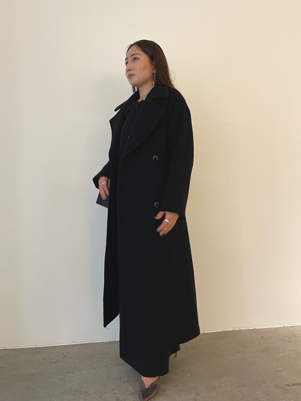 シルバー系のパンプス、ブラック系のハンドバッグ、ブラック系のドレスを着用したレディースの秋コーディネートの3枚目の写真