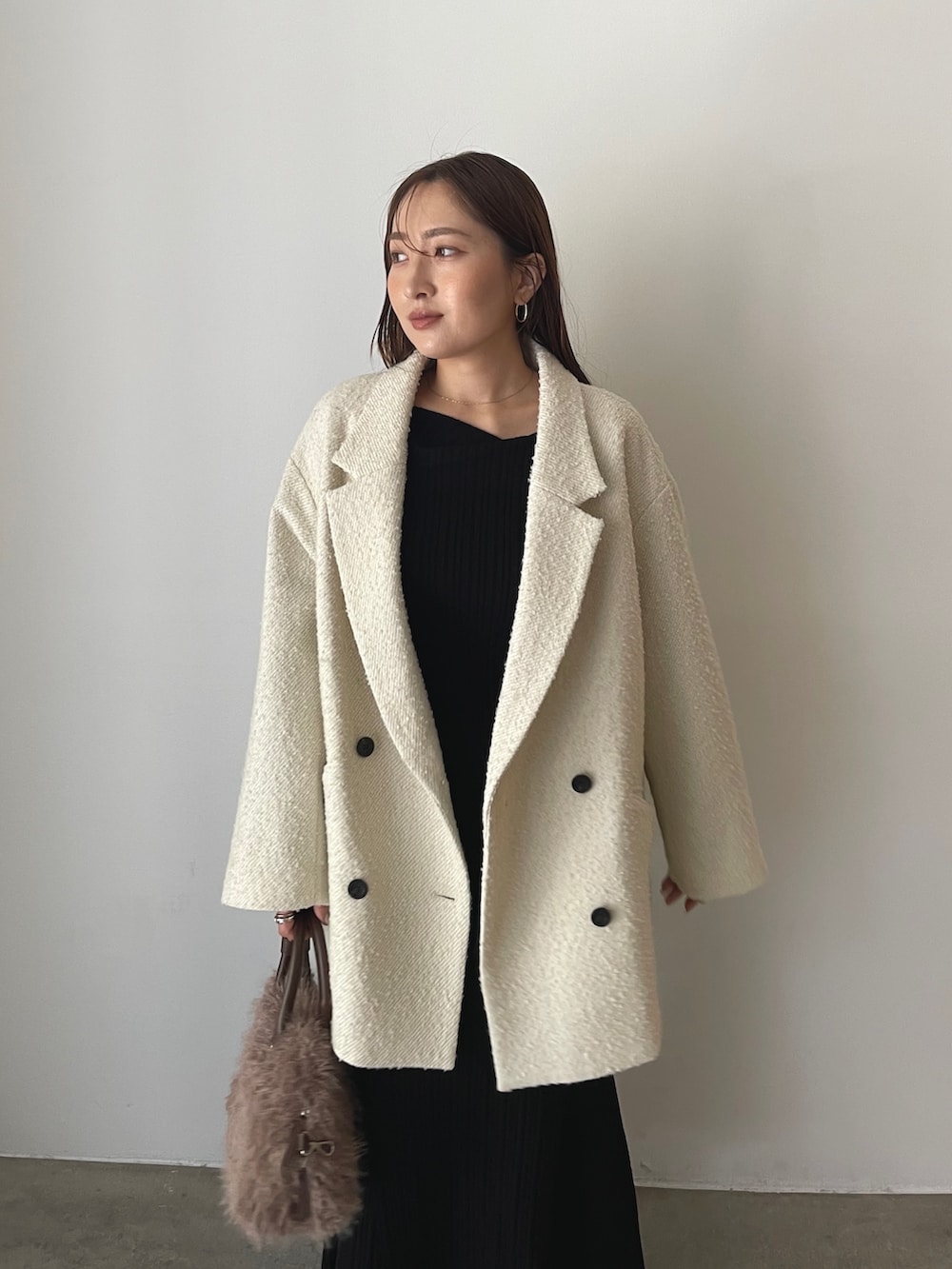 ブラック系のワンピース、ベージュ系のパンプス、ブラウン系のボストンバッグを着用したレディースの秋コーディネートの5枚目の写真