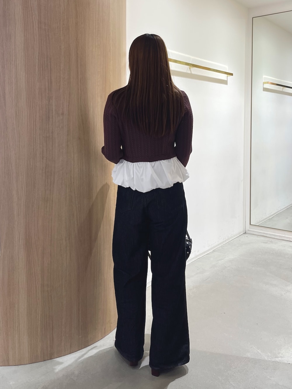 レッド系のブーツ、ブラック系のデニムパンツ、ブラック系のハンドバッグを着用したレディースの秋コーディネートの4枚目の写真