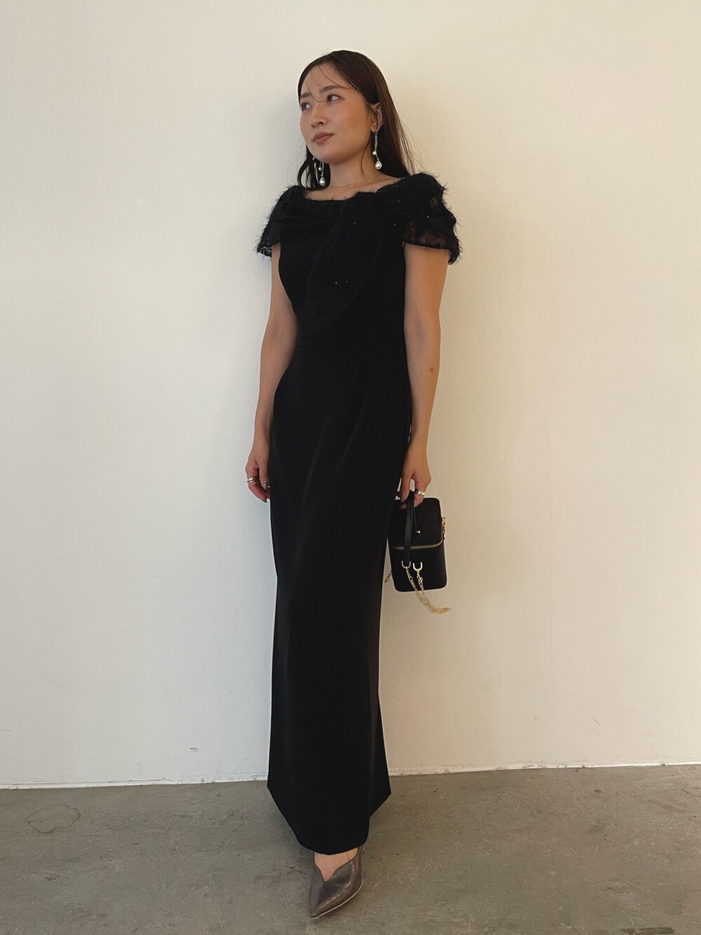 シルバー系のパンプス、ブラック系のハンドバッグ、ブラック系のドレスを着用したレディースの秋コーディネートの9枚目の写真