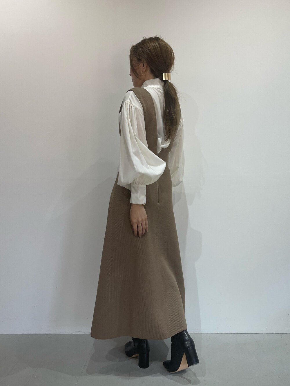 ブラック系のブーツ、ベージュ系のジャンパースカート、ホワイト系のシャツ/ブラウスを着用したレディースの秋コーディネートの4枚目の写真