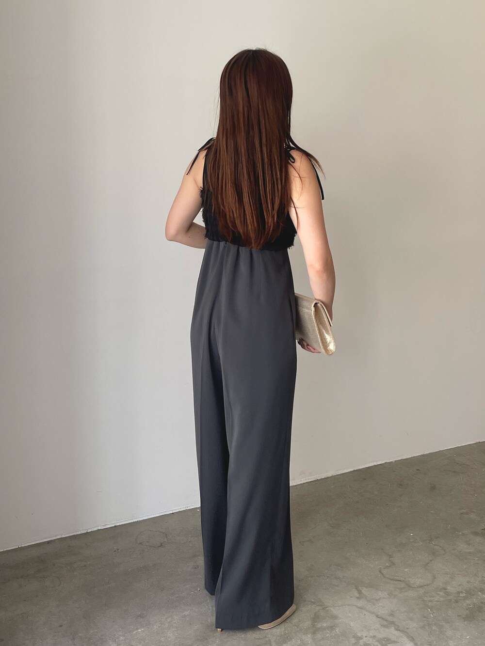 グレー系のパンツドレス、ゴールド系のパンプス、ゴールド系のクラッチバッグを着用したレディースの春コーディネートの7枚目の写真