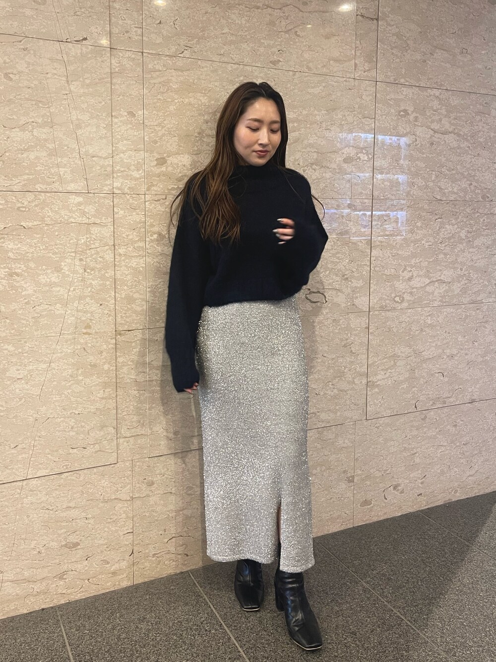 ブラック系のブーツ、ブルー系のニット/セーター、シルバー系のスカートを着用したレディースの冬コーディネートの2枚目の写真