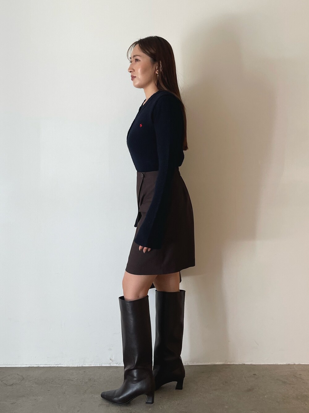 ブラウン系のボストンバッグ、ブラウン系のスカート、ブルー系のニット/セーターを着用したレディースの夏コーディネートの5枚目の写真