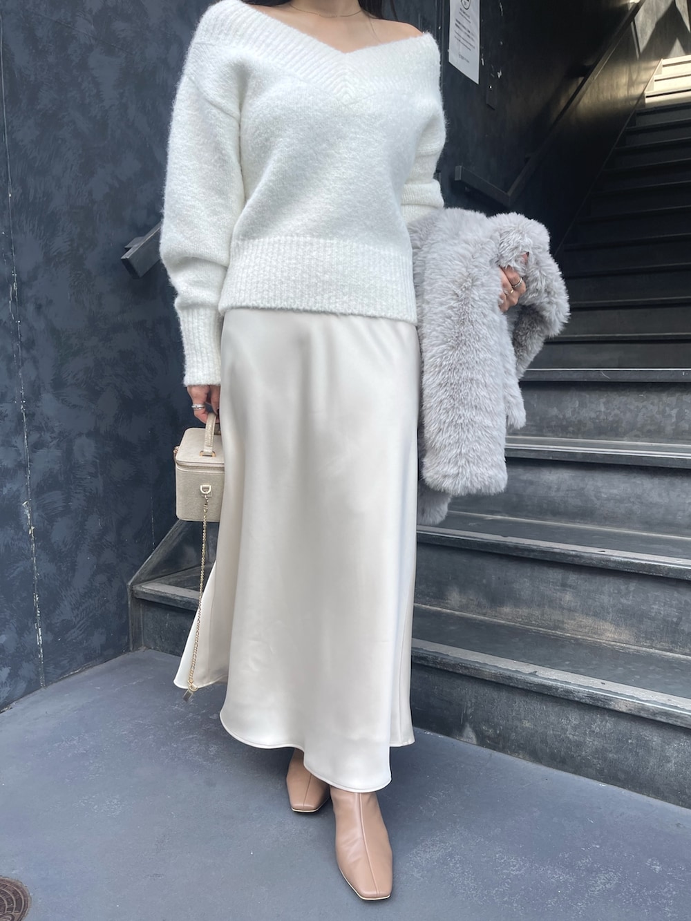 ホワイト系のニット/セーター、グレー系のその他アウター、ゴールド系のハンドバッグを着用したレディースの冬コーディネートの9枚目の写真