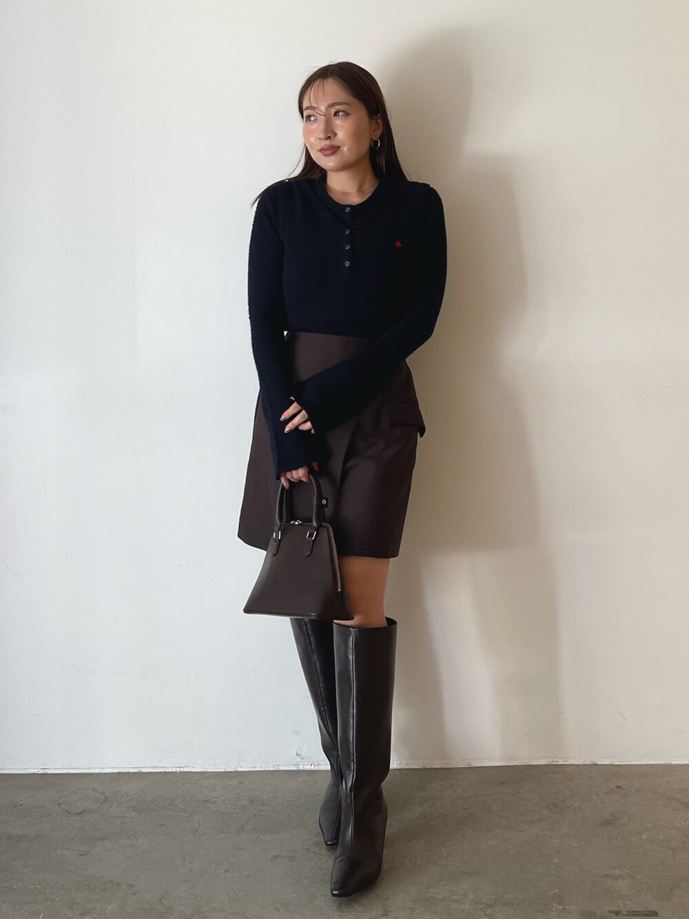 ブラウン系のボストンバッグ、ブラウン系のスカート、ブルー系のニット/セーターを着用したレディースの夏コーディネートの2枚目の写真