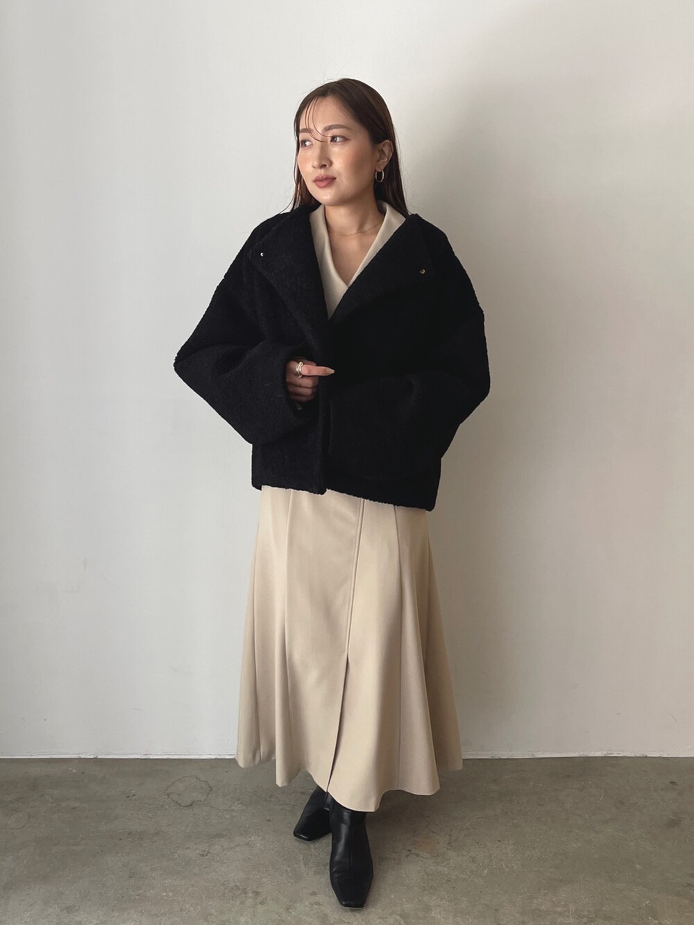 イエロー系のハンドバッグ、ブラック系のブルゾン、ベージュ系のワンピースを着用したレディースの秋コーディネートの5枚目の写真