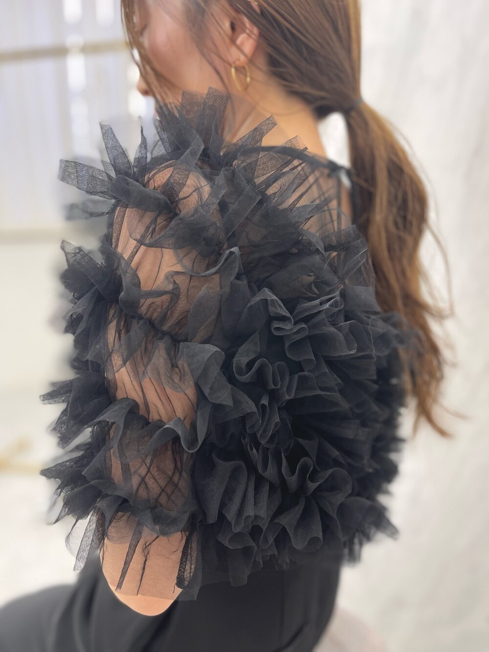 ブラック系のパンツドレス、ゴールド系のパンプスを着用したレディースの冬コーディネートの8枚目の写真