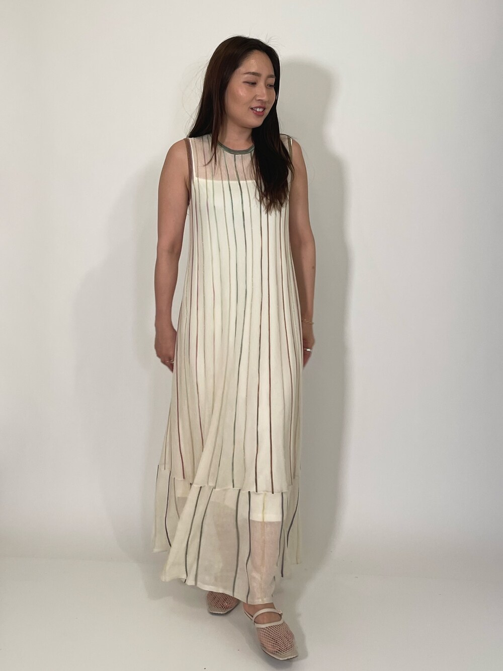 ホワイト系のサンダル、ホワイト系のワンピース、ゴールド系のブレスレットを着用したレディースの夏コーディネートの3枚目の写真