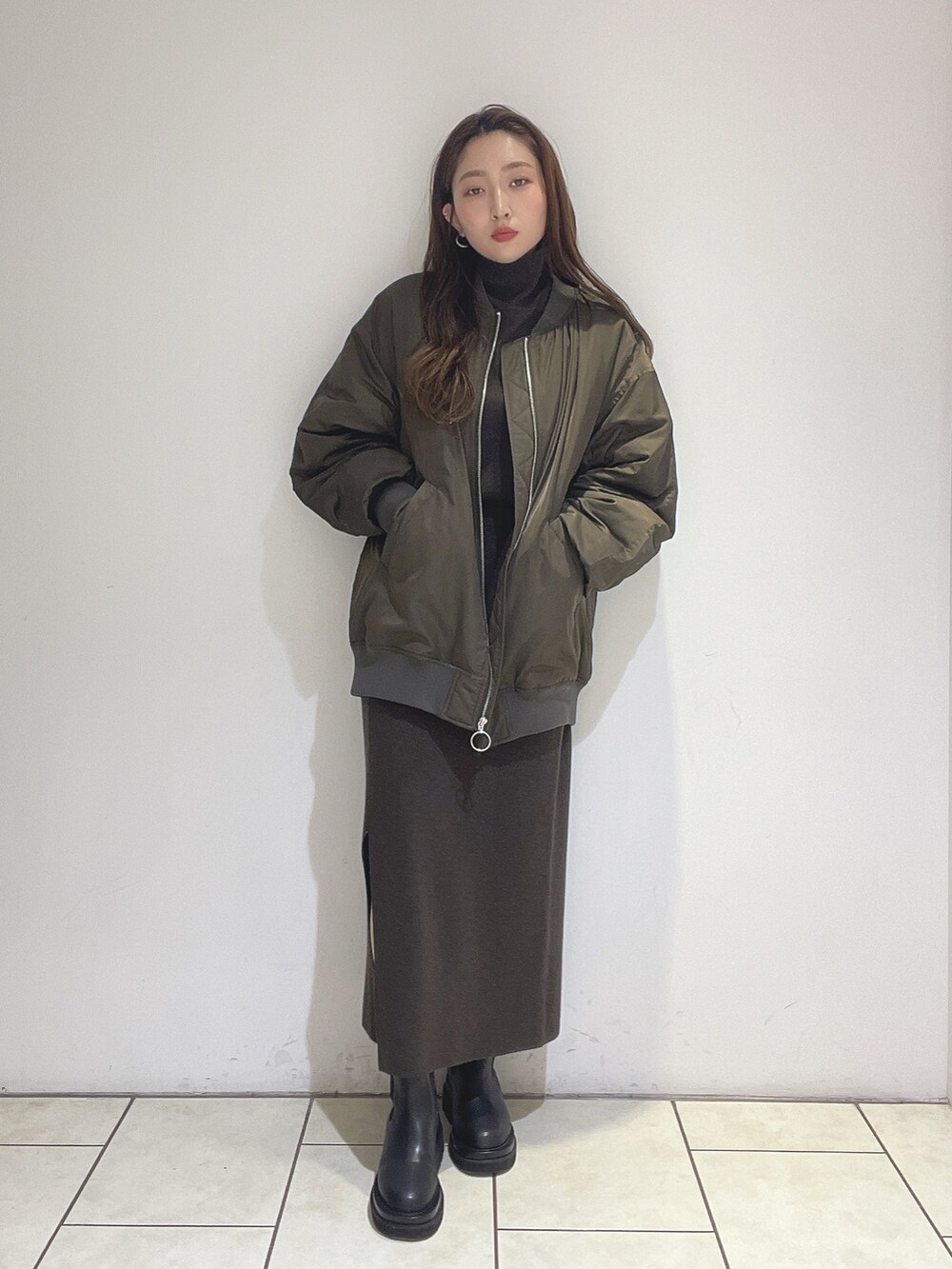 ブラウン系のニット/セーター、ブラウン系のスカート、ブラック系のブーツを着用したレディースの冬コーディネートの2枚目の写真