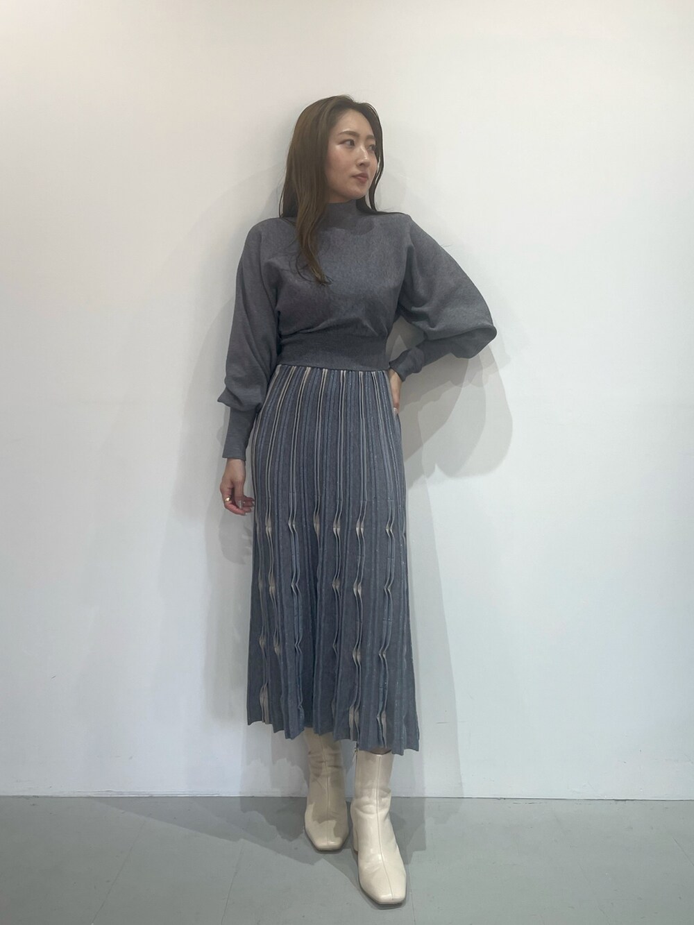 ホワイト系のブーツ、グレー系のワンピースを着用したレディースの秋コーディネートの2枚目の写真