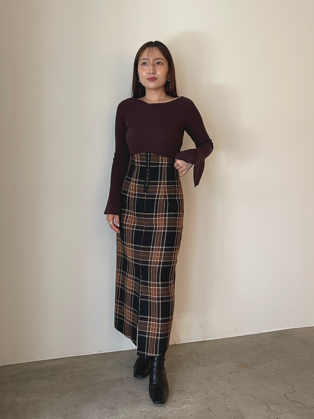 ブラック系のブーツ、ブラウン系のスカート、ブラウン系のニット/セーターを着用したレディースの秋コーディネートの2枚目の写真