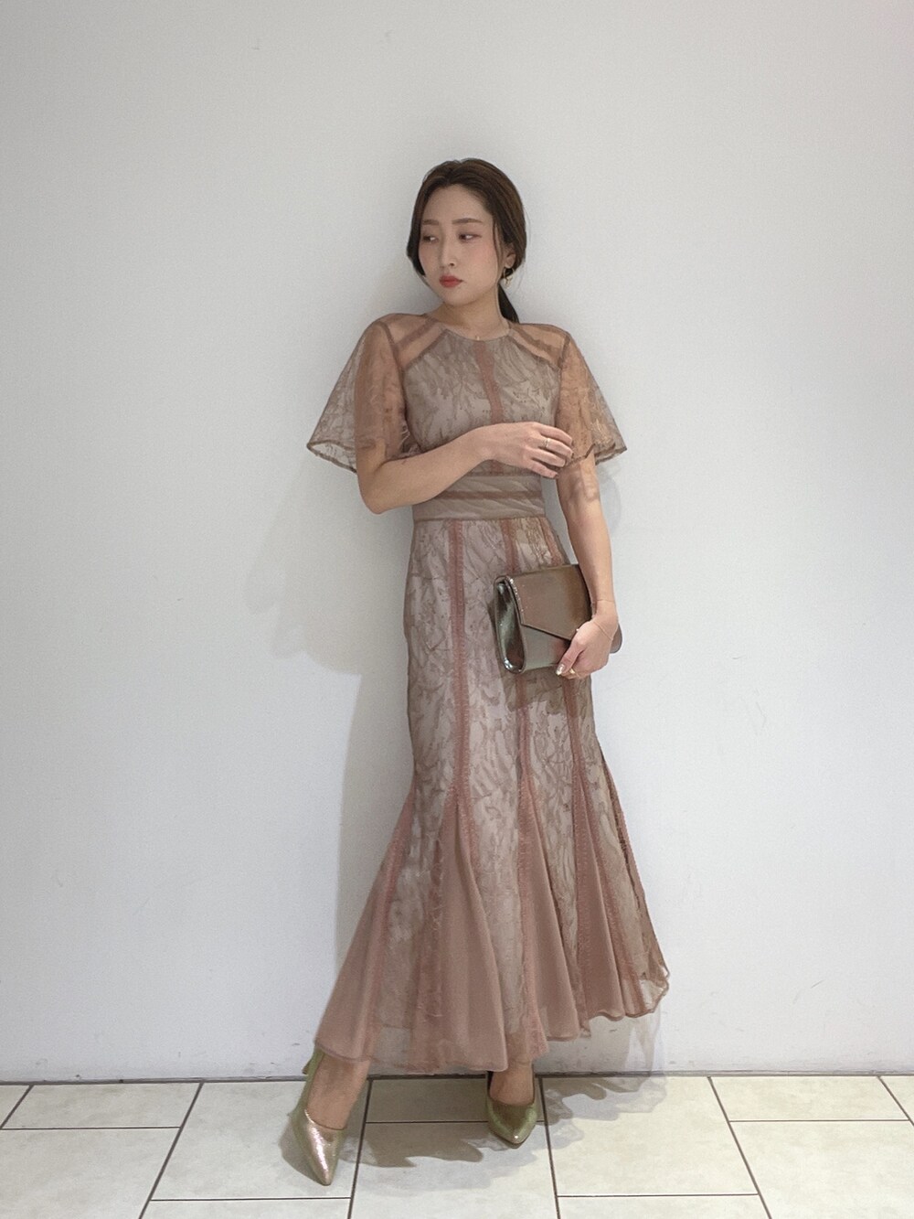 ブラウン系のドレス、ゴールド系のパンプス、ゴールド系のハンドバッグを着用したレディースの冬コーディネートの2枚目の写真