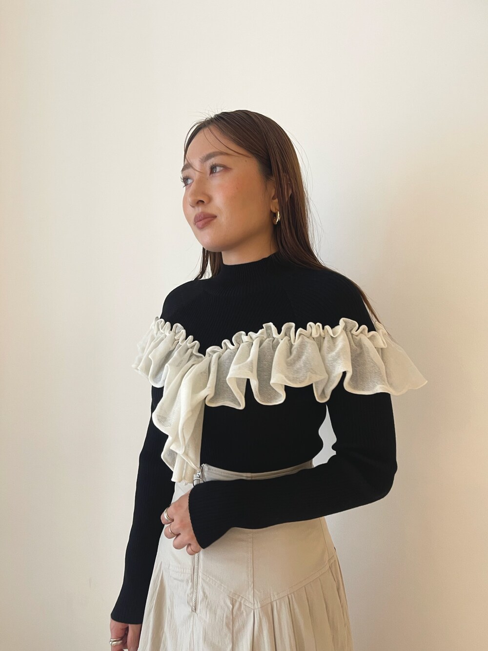 ブラック系のブーツ、ホワイト系のスカート、ブラック系のニット/セーターを着用したレディースの秋コーディネートの9枚目の写真