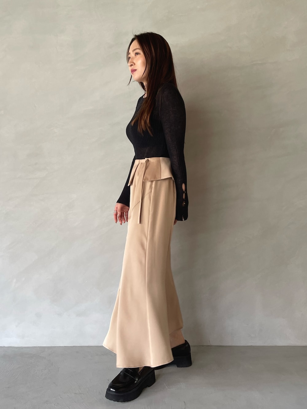 ベージュ系のスカート、ブラック系のニット/セーターを着用したレディースの夏コーディネートの6枚目の写真