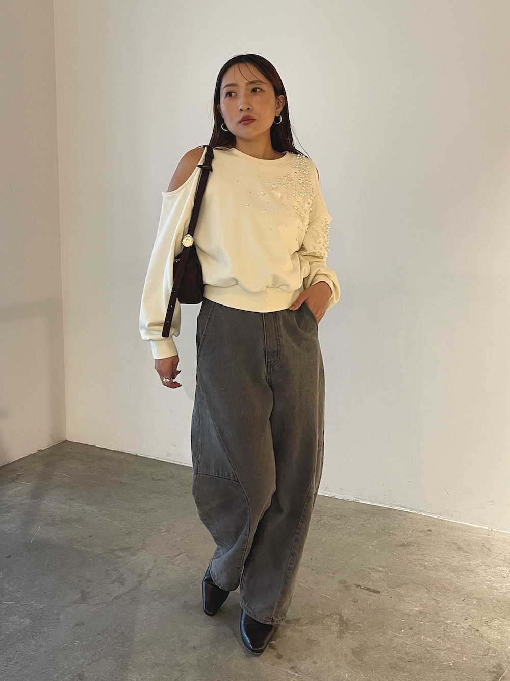 グレー系のデニムパンツ、ブラック系のブーツ、ブラウン系のハンドバッグを着用したレディースの秋コーディネートの7枚目の写真