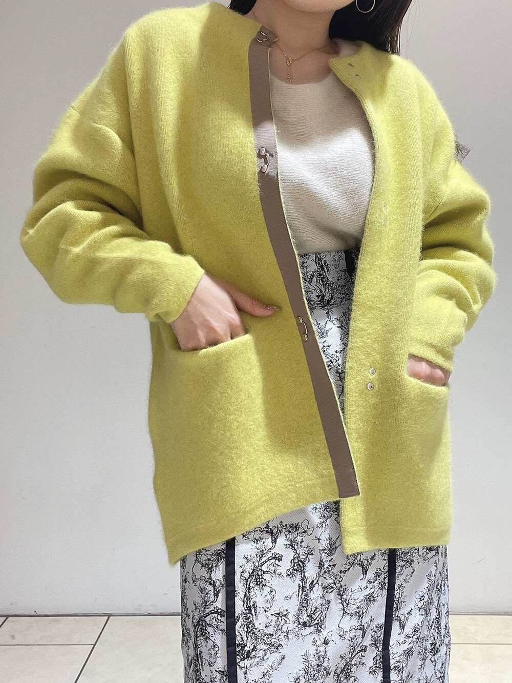 イエロー系のカーディガン/ボレロ、ブラック系のスカート、ホワイト系のニット/セーターを着用したレディースの秋コーディネートの7枚目の写真