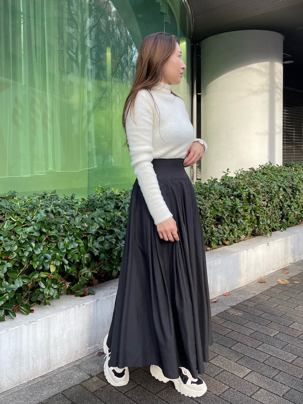 ブラック系のスニーカー、ホワイト系のニット/セーター、ブラック系のスカートを着用したレディースの冬コーディネートの2枚目の写真