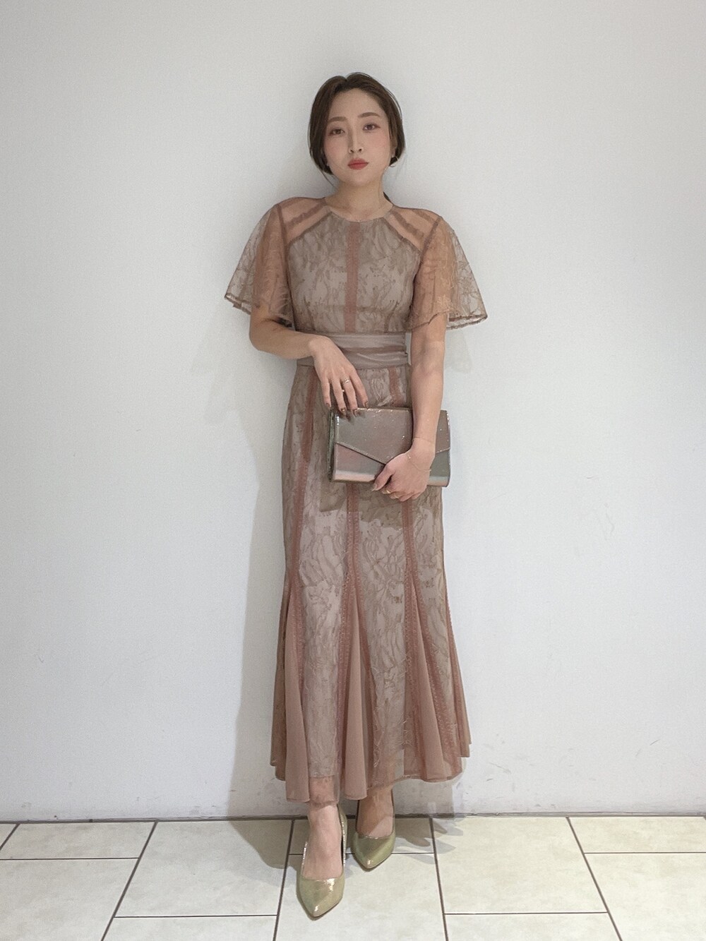 ブラウン系のドレス、ゴールド系のパンプス、ゴールド系のハンドバッグを着用したレディースの冬コーディネートの3枚目の写真