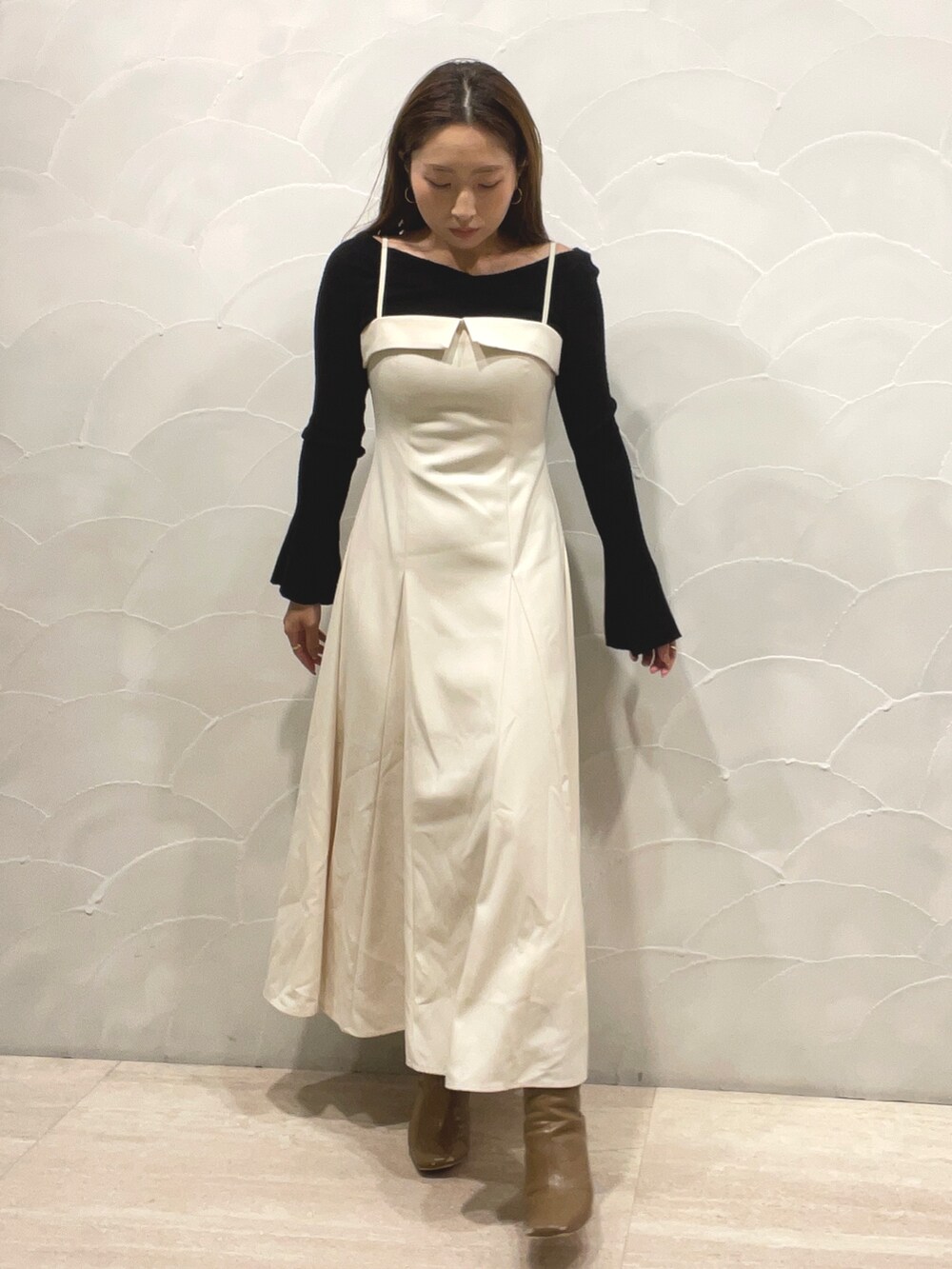 ベージュ系のブーツ、ブラック系のニット/セーター、ホワイト系のワンピースを着用したレディースの秋コーディネートの7枚目の写真