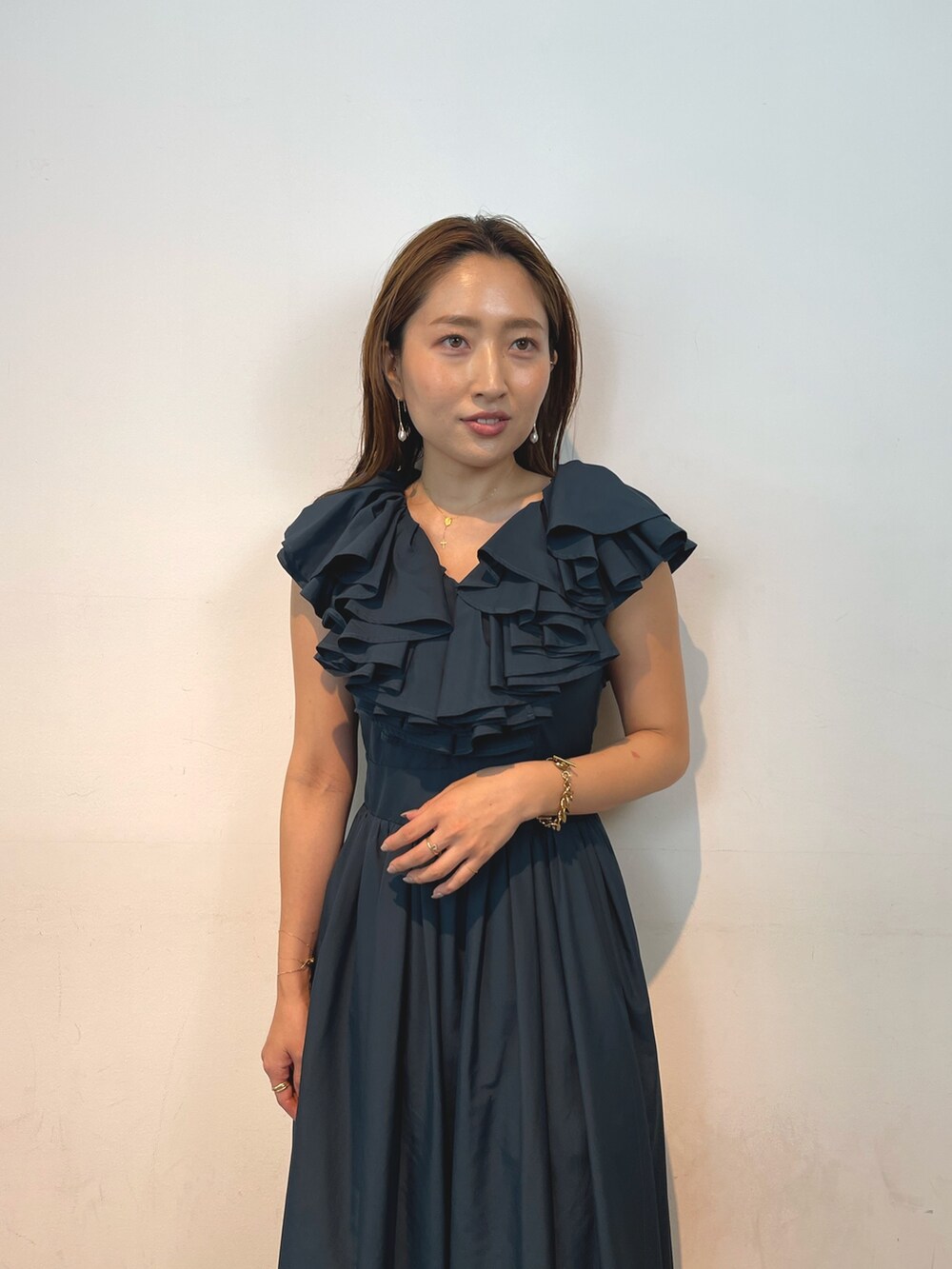 ベージュ系のパンプス、グリーン系のドレス、ゴールド系のピアス（両耳用）を着用したレディースの夏コーディネートの5枚目の写真