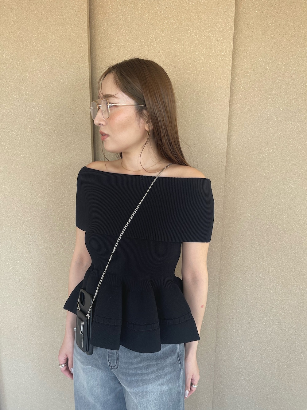 ブラック系のニット/セーター、グレー系のデニムパンツ、オレンジ系のサンダルを着用したレディースの春コーディネートの8枚目の写真