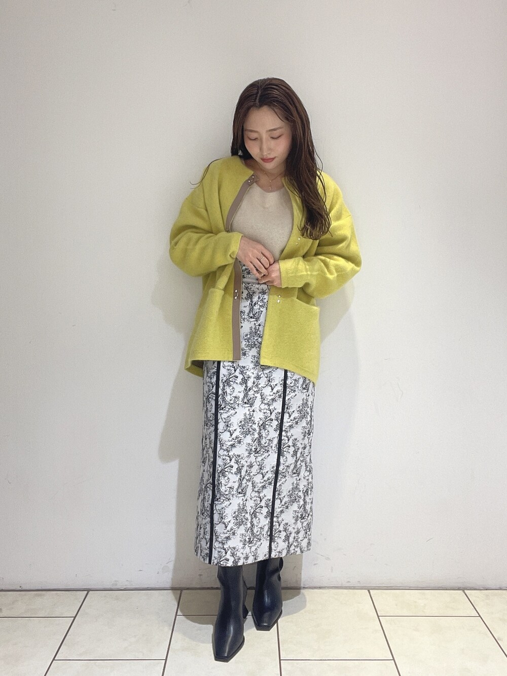 イエロー系のカーディガン/ボレロ、ブラック系のスカート、ホワイト系のニット/セーターを着用したレディースの秋コーディネートの2枚目の写真