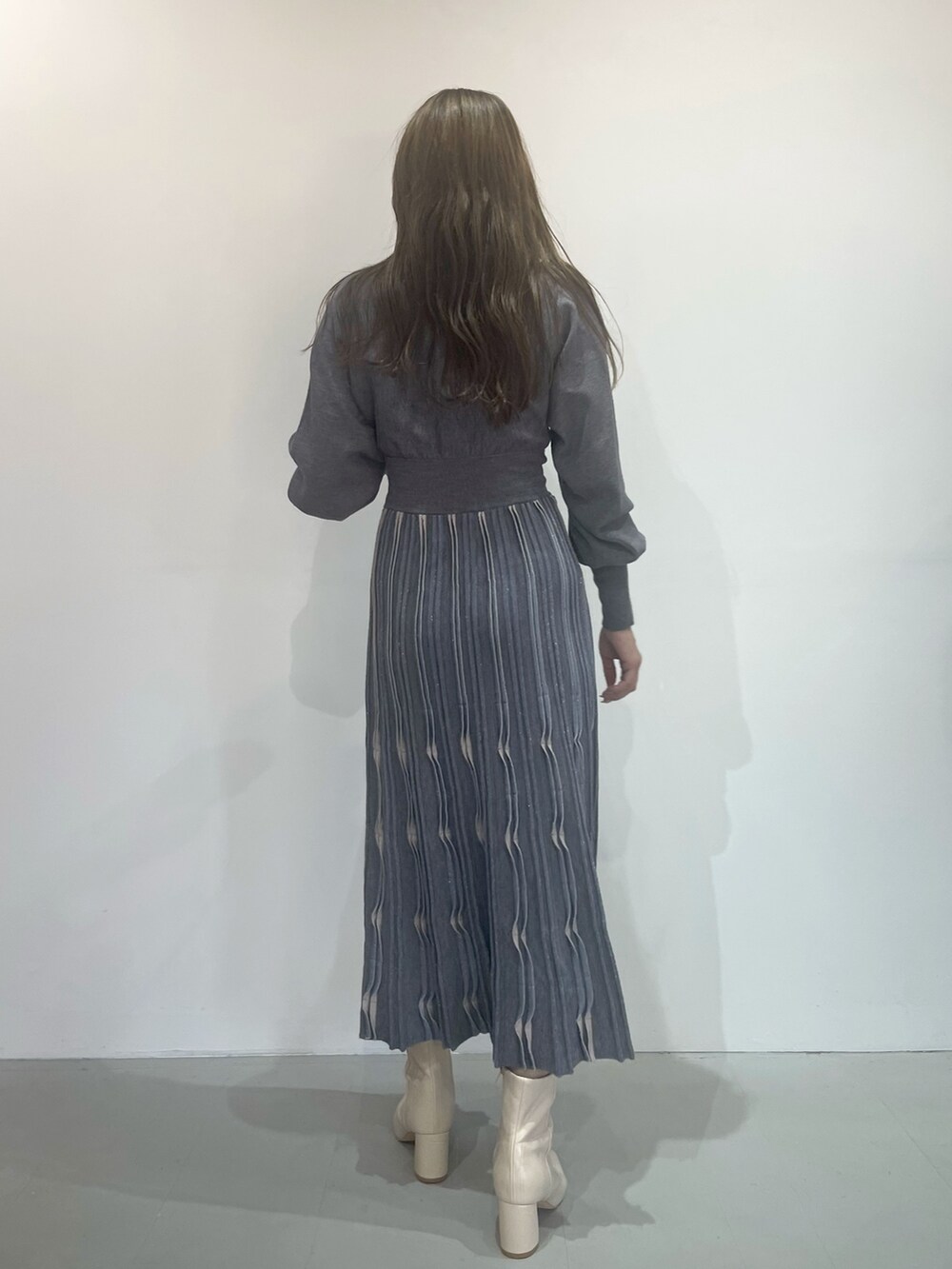 ホワイト系のブーツ、グレー系のワンピースを着用したレディースの秋コーディネートの4枚目の写真