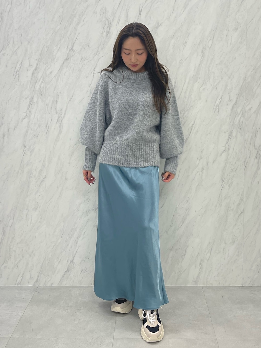 グレー系のニット/セーター、ブルー系のスカート、ブラック系のスニーカーを着用したレディースの冬コーディネートの5枚目の写真