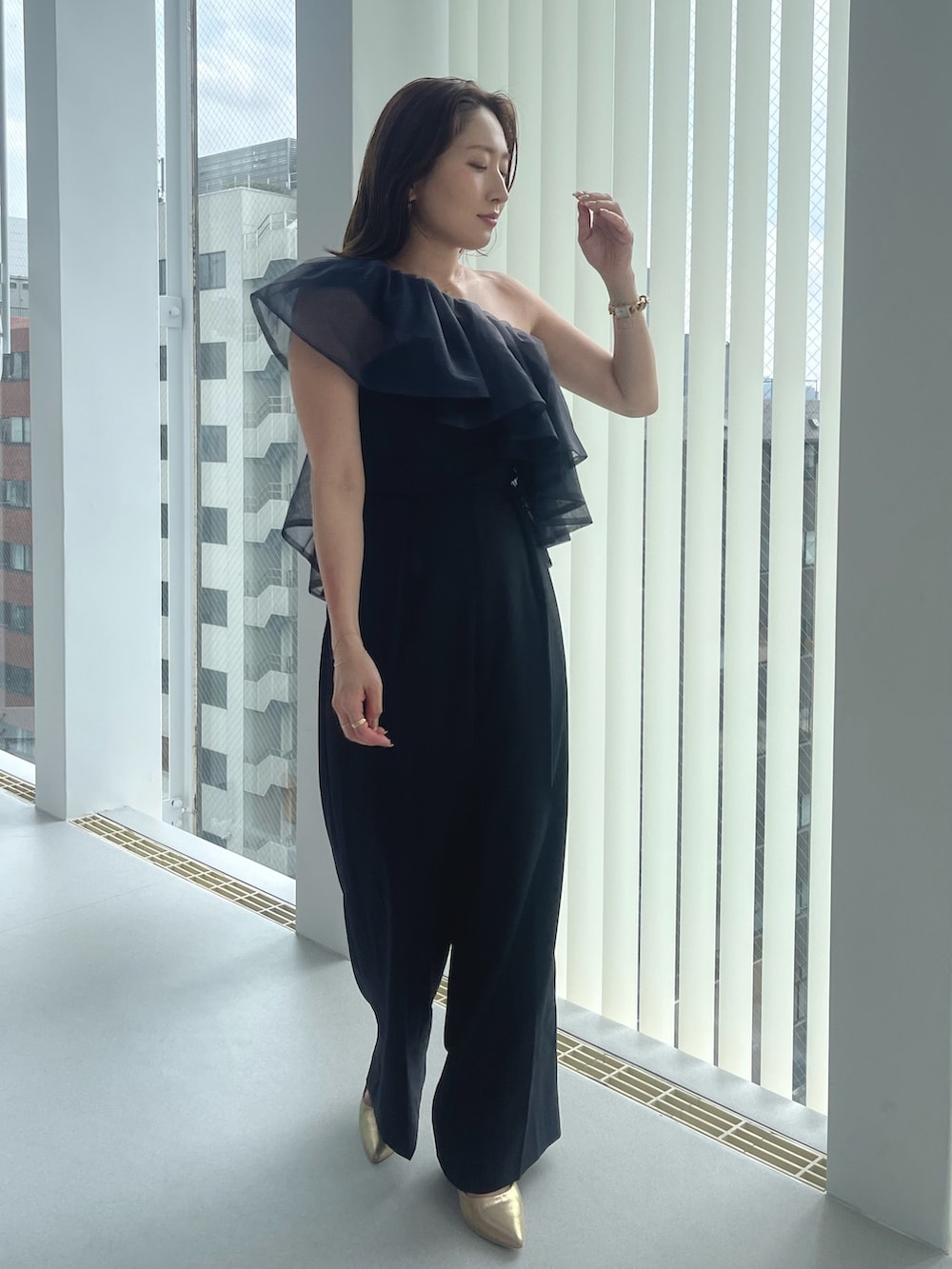 ゴールド系のパンプス、ブラック系のパンツドレスを着用したレディースの夏コーディネートの2枚目の写真