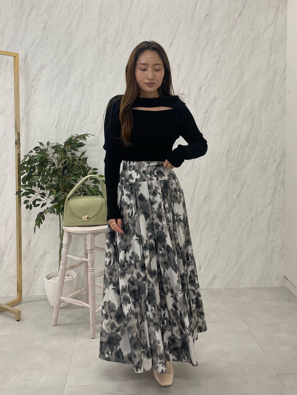 ホワイト系のブーツ、ブラック系のニット/セーター、グリーン系のハンドバッグを着用したレディースの冬コーディネートの3枚目の写真