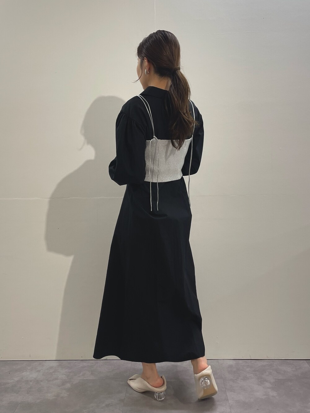 ホワイト系のパンプス、ブラック系のシャツワンピース、シルバー系のイヤリングを着用したレディースの冬コーディネートの5枚目の写真