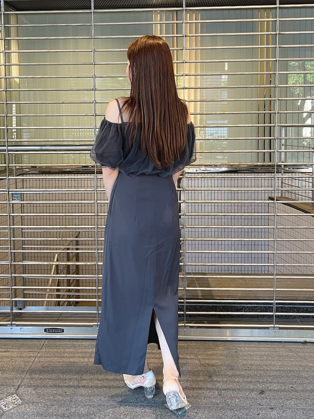 グレー系のドレス、ゴールド系のクラッチバッグ、ゴールド系のピアス（両耳用）を着用したレディースの夏コーディネートの8枚目の写真