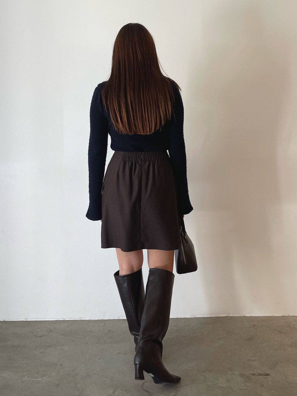 ブラウン系のボストンバッグ、ブラウン系のスカート、ブルー系のニット/セーターを着用したレディースの夏コーディネートの6枚目の写真