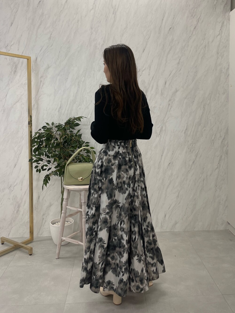 ホワイト系のブーツ、ブラック系のニット/セーター、グリーン系のハンドバッグを着用したレディースの冬コーディネートの6枚目の写真