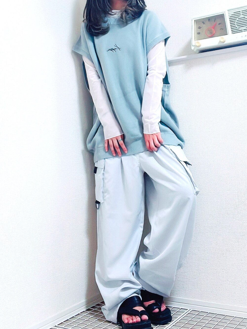 ホワイト系のトップス、ホワイト系のベスト、ブラック系のサンダルを着用したレディースの夏コーディネートの2枚目の写真