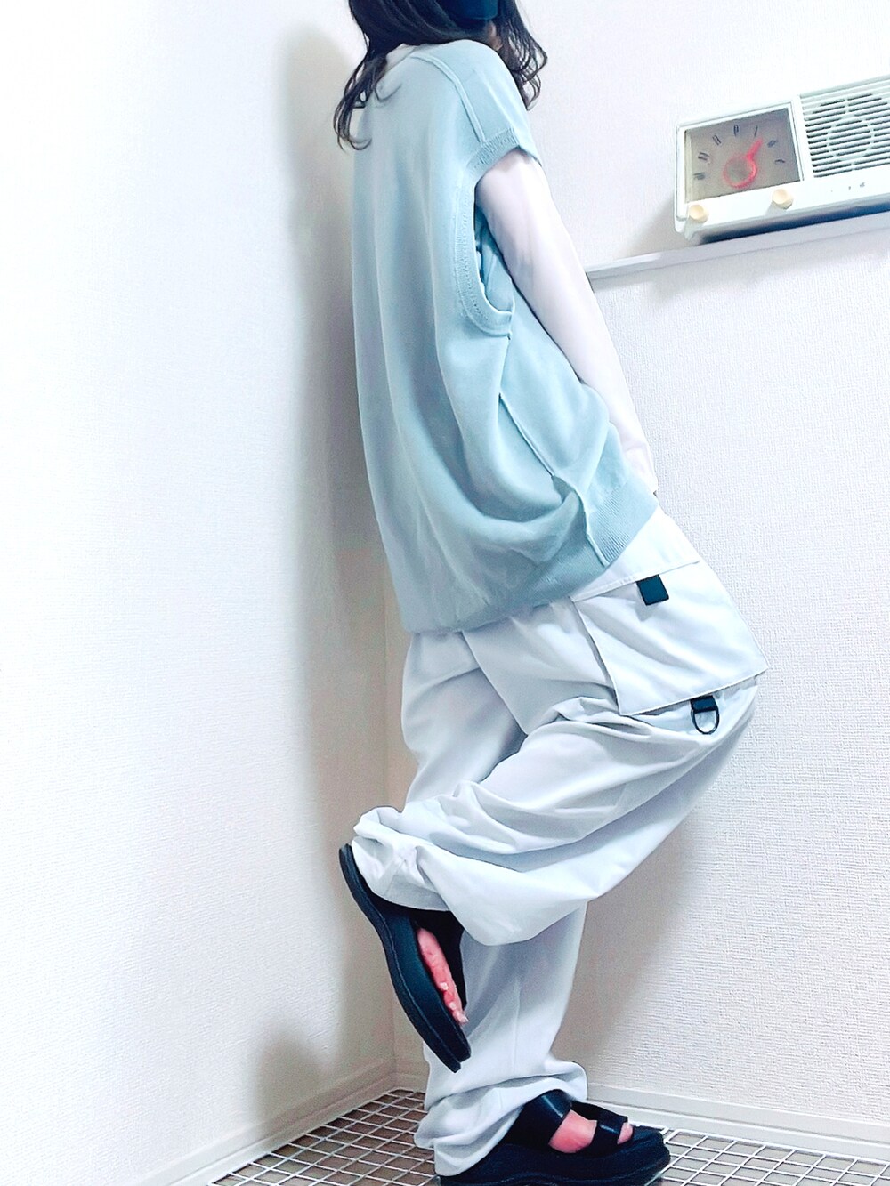 ホワイト系のトップス、ホワイト系のベスト、ブラック系のサンダルを着用したレディースの夏コーディネートの3枚目の写真