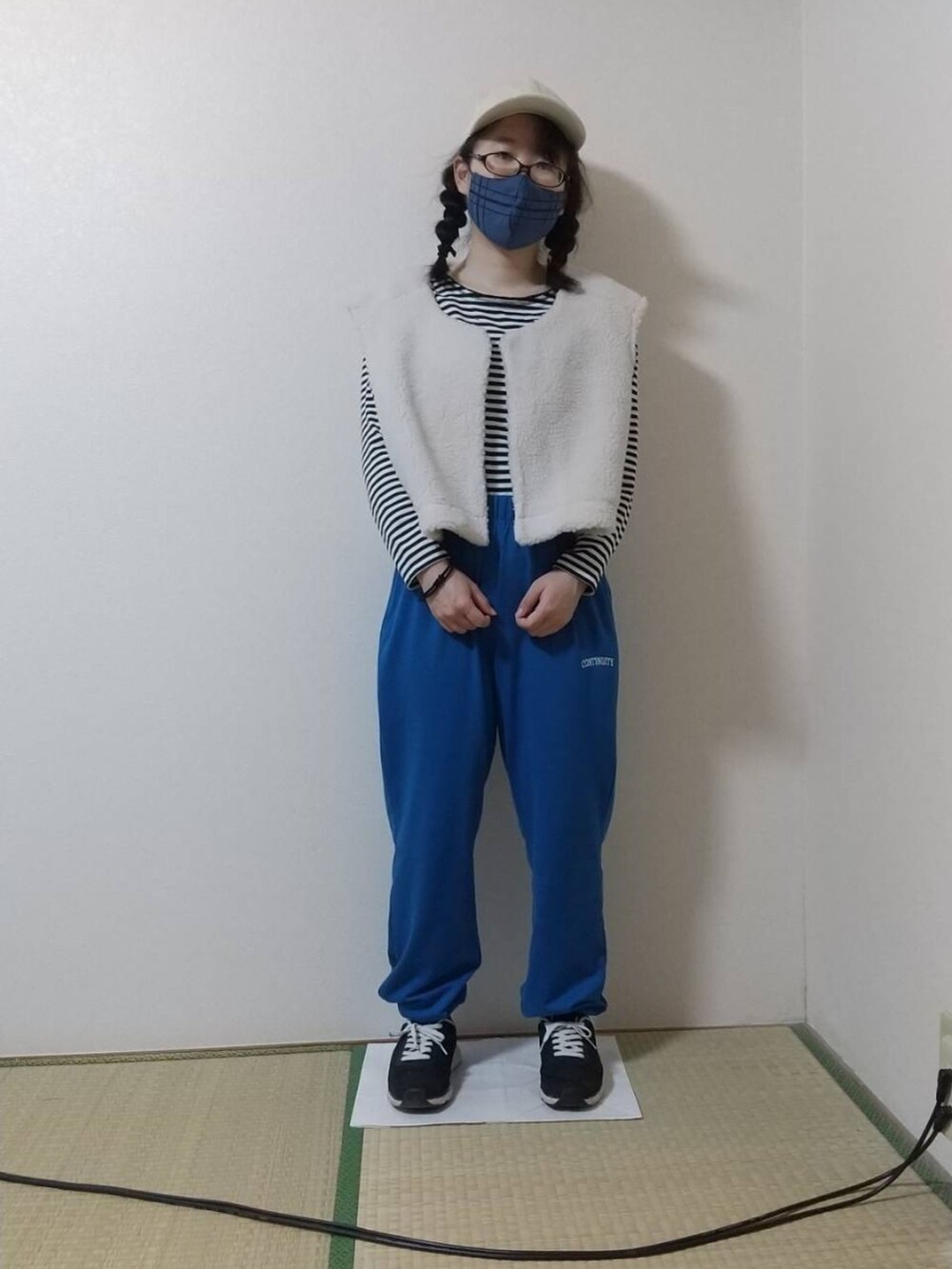 ブラック系のTシャツ/カットソー、ホワイト系のベスト、ブルー系のスウェットパンツを着用したレディースの秋コーディネートの2枚目の写真