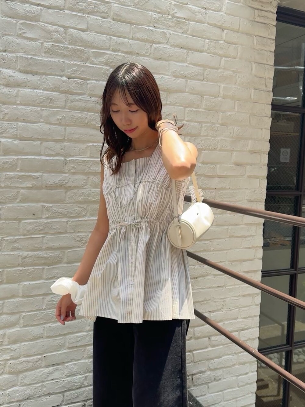 ベージュ系のシャツ/ブラウス、ブラック系のデニムパンツを着用したレディースの夏コーディネートの2枚目の写真