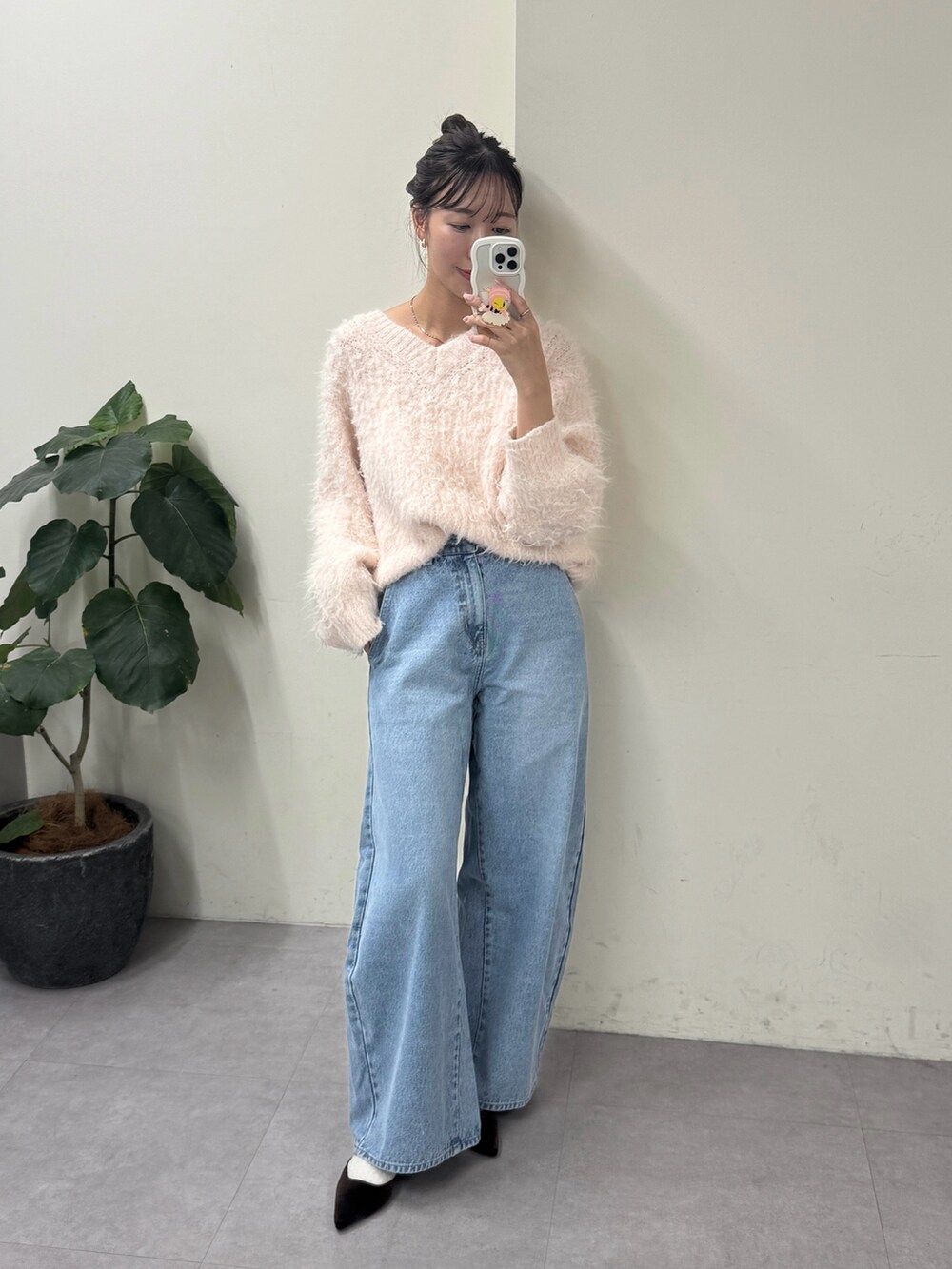 ピンク系のニット/セーター、ブルー系のデニムパンツ、ブラック系のパンプスを着用したレディースの冬コーディネートの2枚目の写真