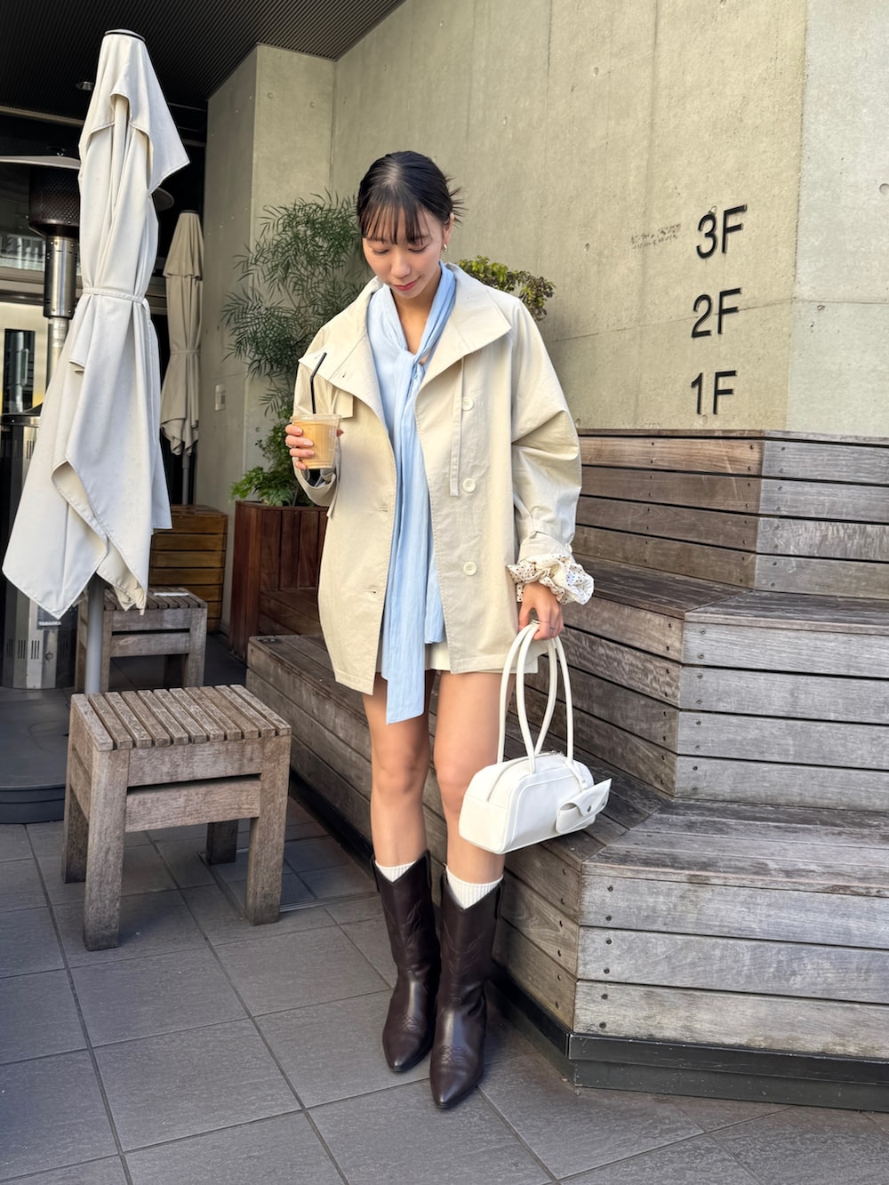 ホワイト系のトレンチコート、ブラウン系のブーツを着用したレディースの冬コーディネートの2枚目の写真