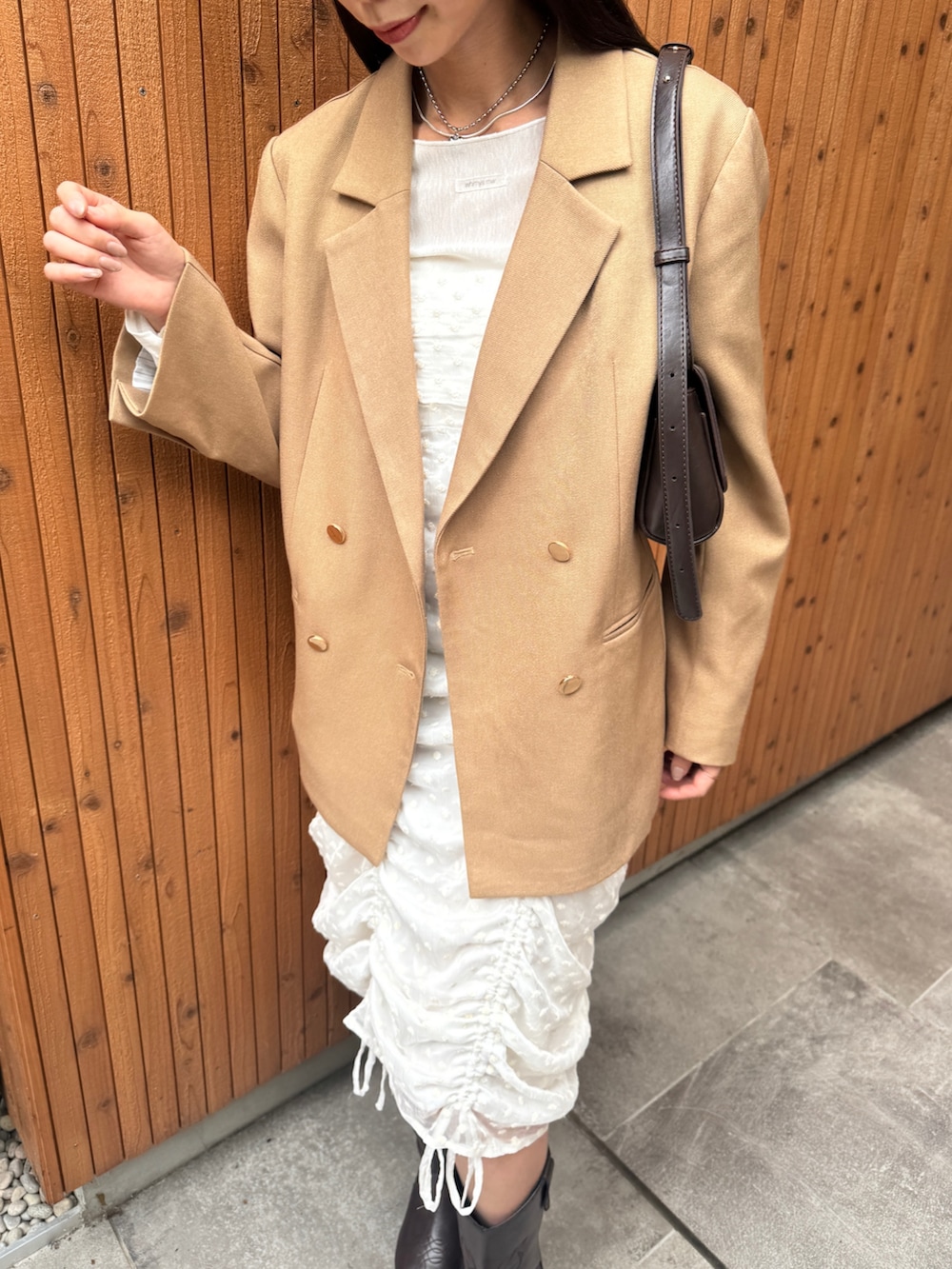 ベージュ系のテーラードジャケット、ブラウン系のトートバッグ、ホワイト系のワンピースを着用したレディースの冬コーディネートの3枚目の写真