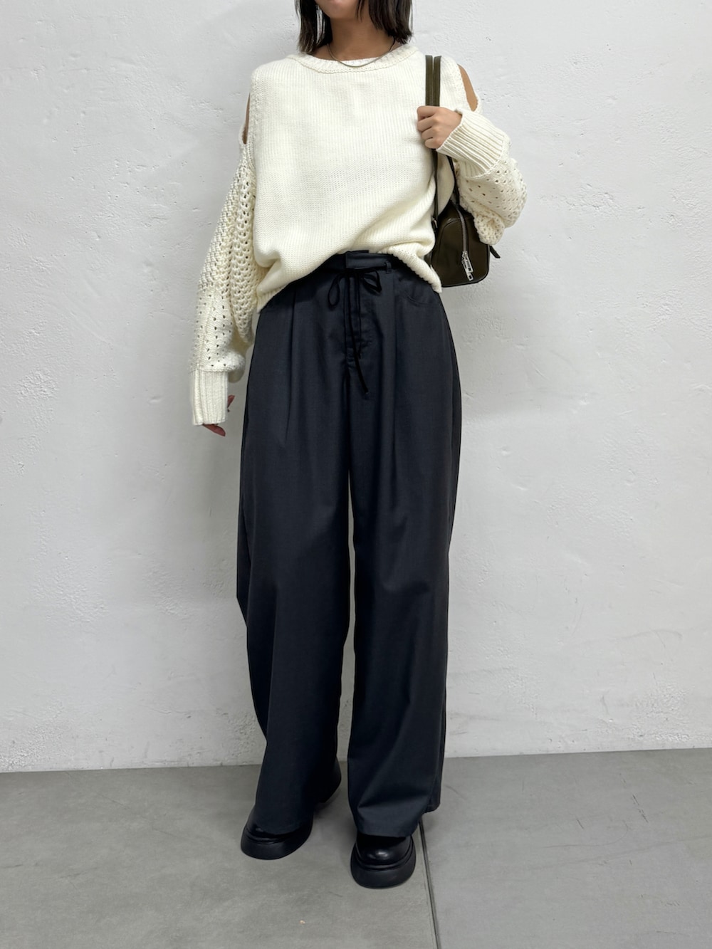 グレー系のスラックス、ホワイト系のニット/セーター、ブラック系のブーツを着用したレディースの秋コーディネートの2枚目の写真