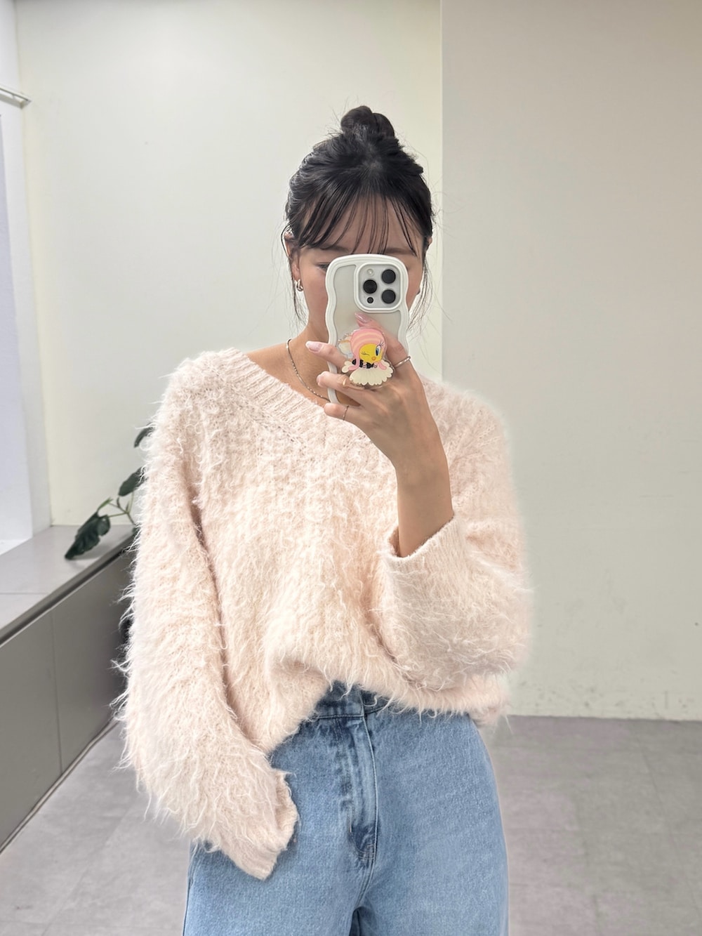 ピンク系のニット/セーター、ブルー系のデニムパンツ、ブラック系のパンプスを着用したレディースの冬コーディネートの3枚目の写真