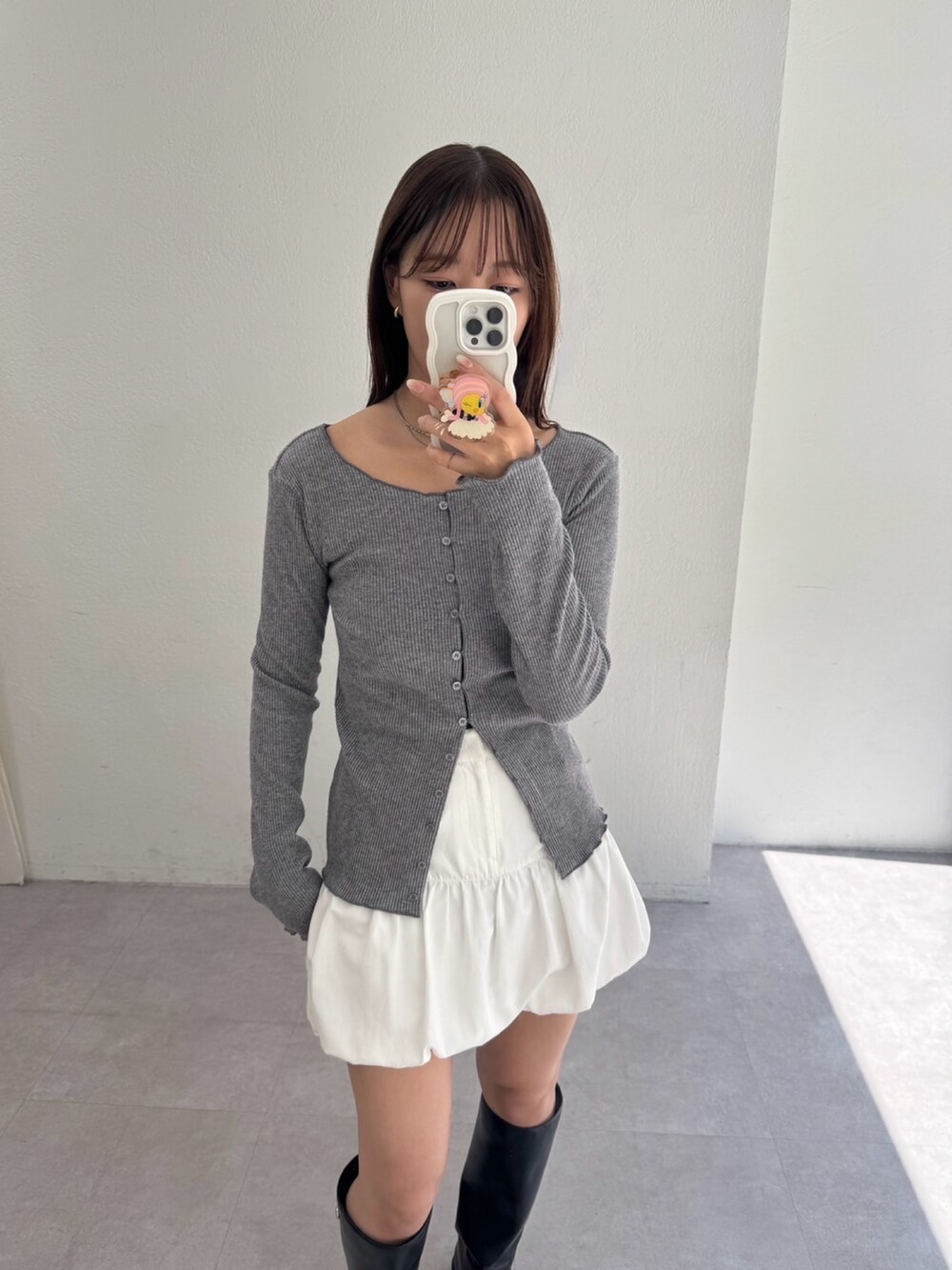グレー系のカーディガン/ボレロ、ホワイト系のスカート、ブラック系のブーツを着用したレディースの夏コーディネートの3枚目の写真