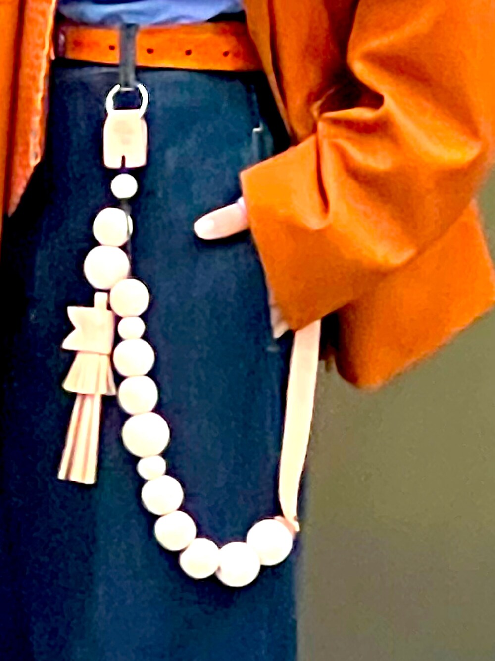 ブルー系のデニムパンツ、ブラック系のブーツ、オレンジ系のバッグを着用したメンズの秋コーディネートの4枚目の写真